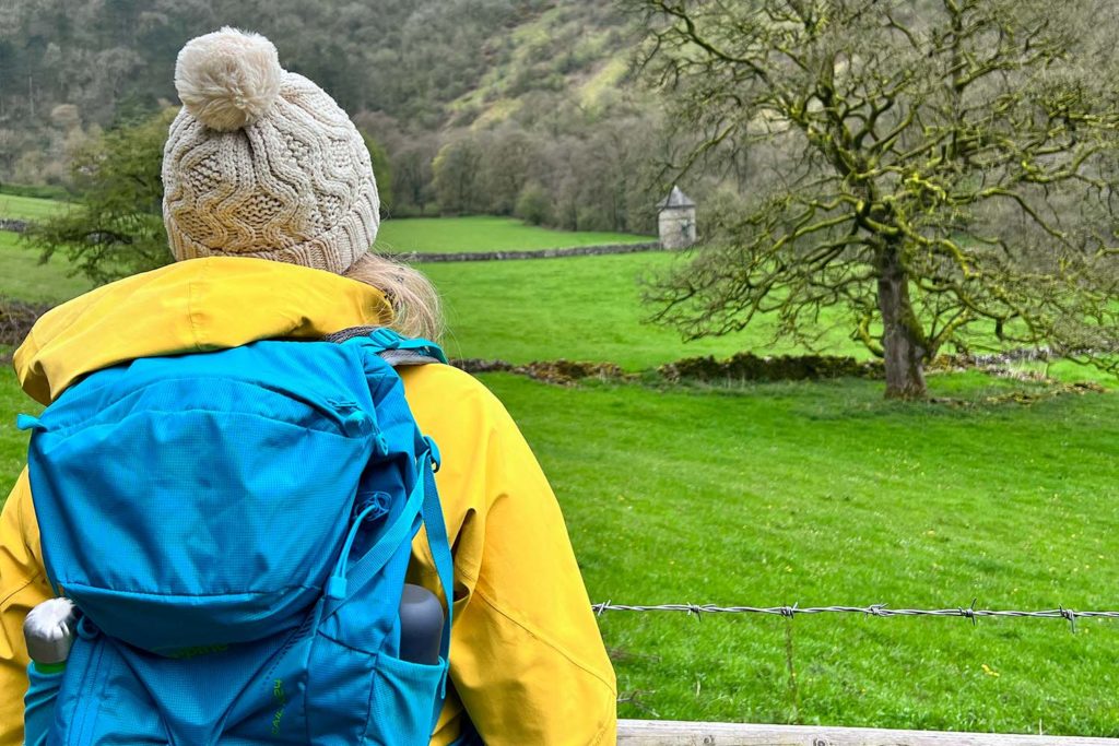 Jen Lowthrop with packpack on looking out at a field in the Peak District